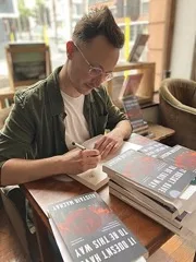 An author signing copies of their own book at a bookshop