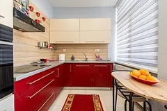 A modern kitchen with red cabinets and a wooden table