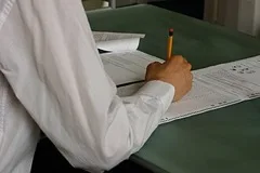 A hand writing on a multiple-choice exam answer sheet