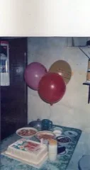 A birthday party table with balloons and a cake