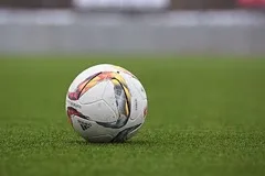 A soccer ball resting on a grass pitch
