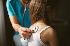 A female doctor listening to a patient with a stethoscope