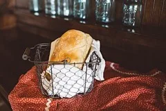 A loaf of bread wrapped in cloth in a wire basket