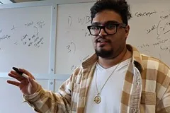A teacher gesturing while presenting at a whiteboard